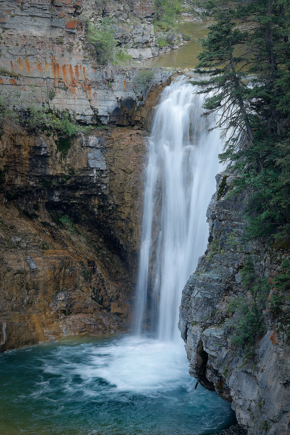 A tall waterfall plunges into a canyon.