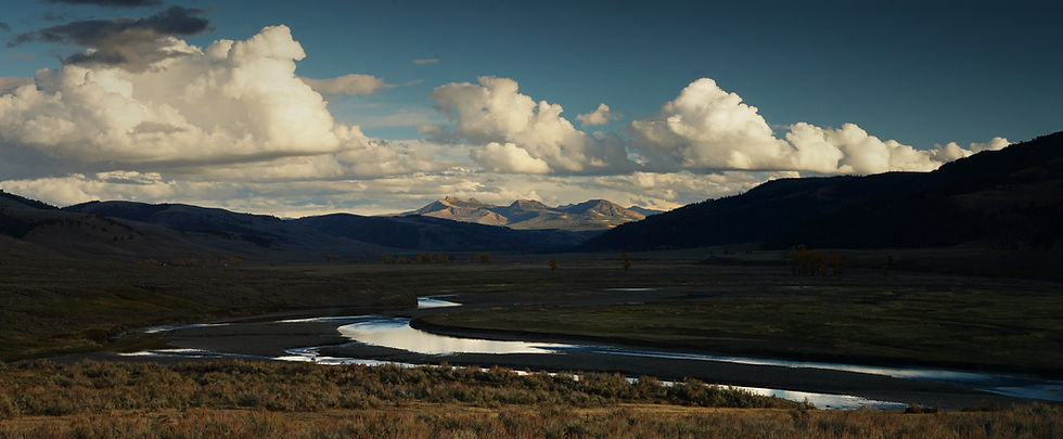 Distant mountains and clouds overhead, with a river in the foreground
