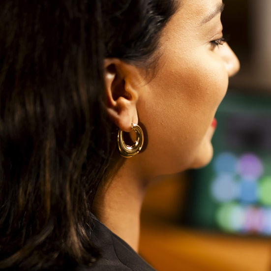mulher de lado usando Brinco Argola de Clique Oval Banhado a Ouro 18k