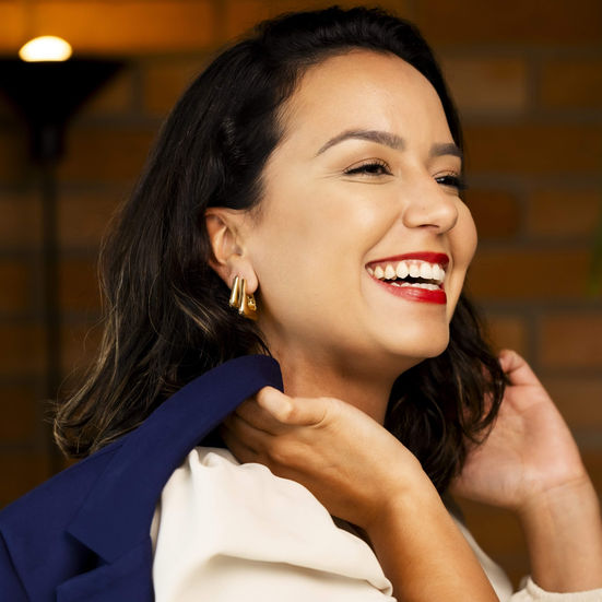 mulher com brinco de clique em formato triangular banhados a ouro 18k sorrindo