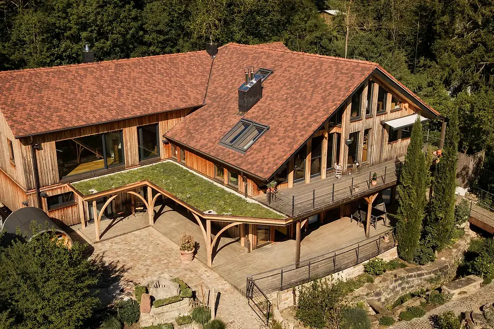Drohenaufnahme eines Landhauses, das Landhaus ist in die gruene Umgebung eingebettet und passt sich organisch an