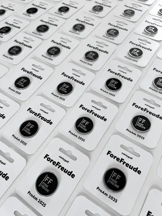 Custom-made B2B ball markers. The ball markers are attached to paper cards. The image shows many finished products