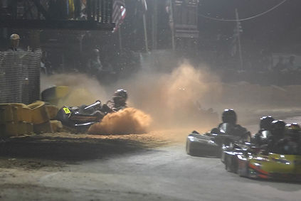 a wreck involving several go karts on a dirt race tracl.