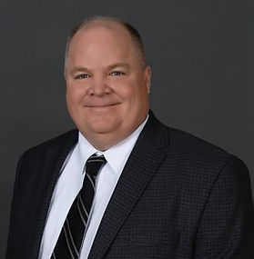 Headshot of Tim Pool, a man wearing suit jacket and tie, smiling.