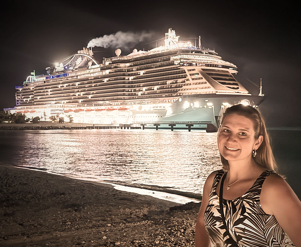 Woman smiling on a beach at night, large cruise ship illuminated in the background. Warm, serene atmosphere with calm water.