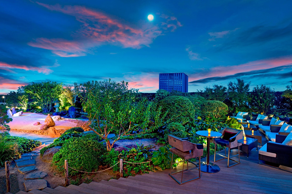 Moonlit serenity at the St. Regis Osaka's garden terrace, a perfect blend of elegant seating and lush greenery under a vibrant evening sky.