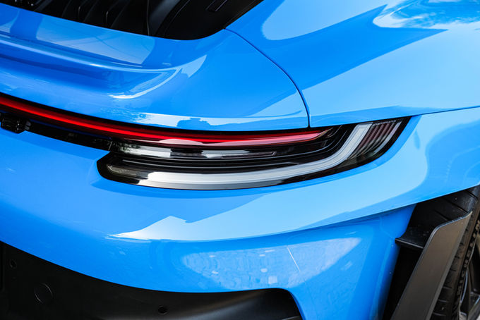 Gros plan sur l’arrière d’une Porsche bleue et son feu rouge horizontal.