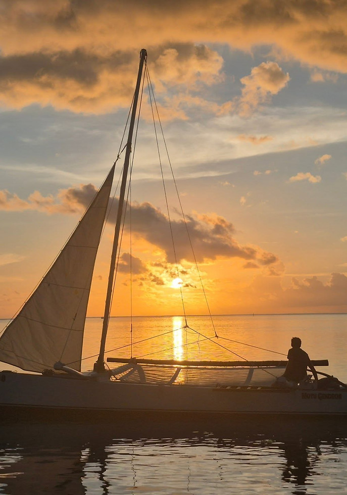 Sailboat with person on calm water at sunset