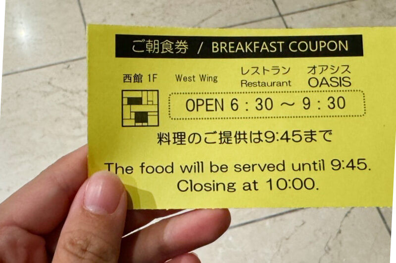 Hand holding the hotel breakfast ticket showing hours from 6:30 to 9:30 and closing time at 10:00.