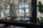 The dining interior of EBISU. Natural light fills the room through arched windows. Cherry blossom decorations are placed between booths and tables.