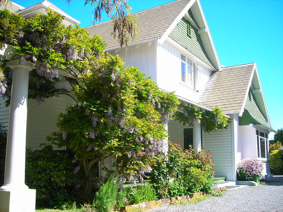 Exterior view of the Southern Cross Language Institute (SCLI) campus building surrounded by greenery and gardens in Christchurch, New Zealand.