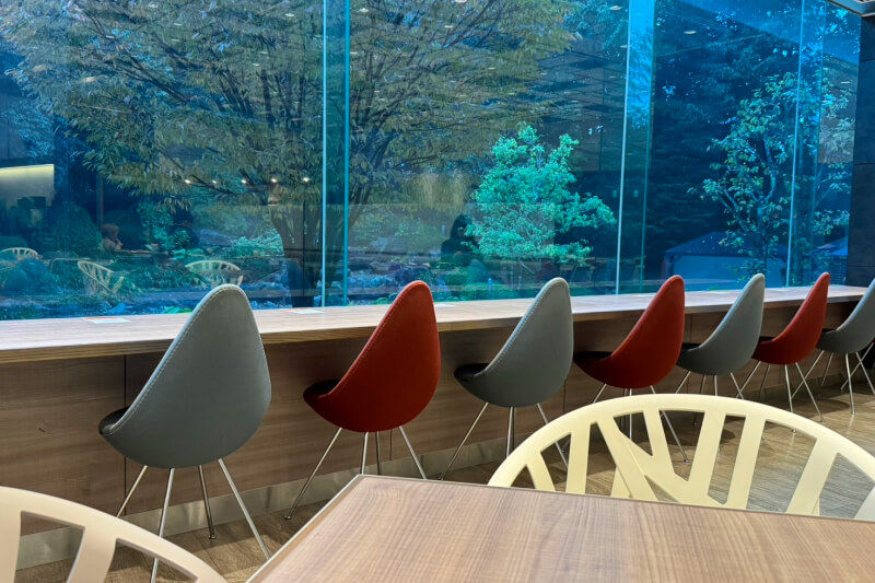 Counter seating with garden views through large windows and mismatched chairs in the calm breakfast area.