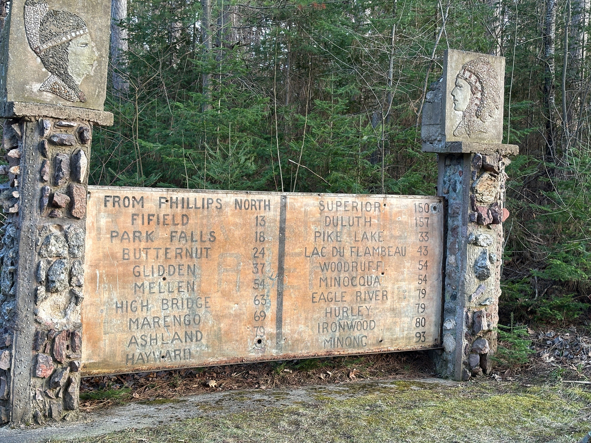 Fred Smith's Wisconsin Concrete Park, outside Phillips, WI. Concrete posts hold sign that lists distances to other Wisconsin towns.