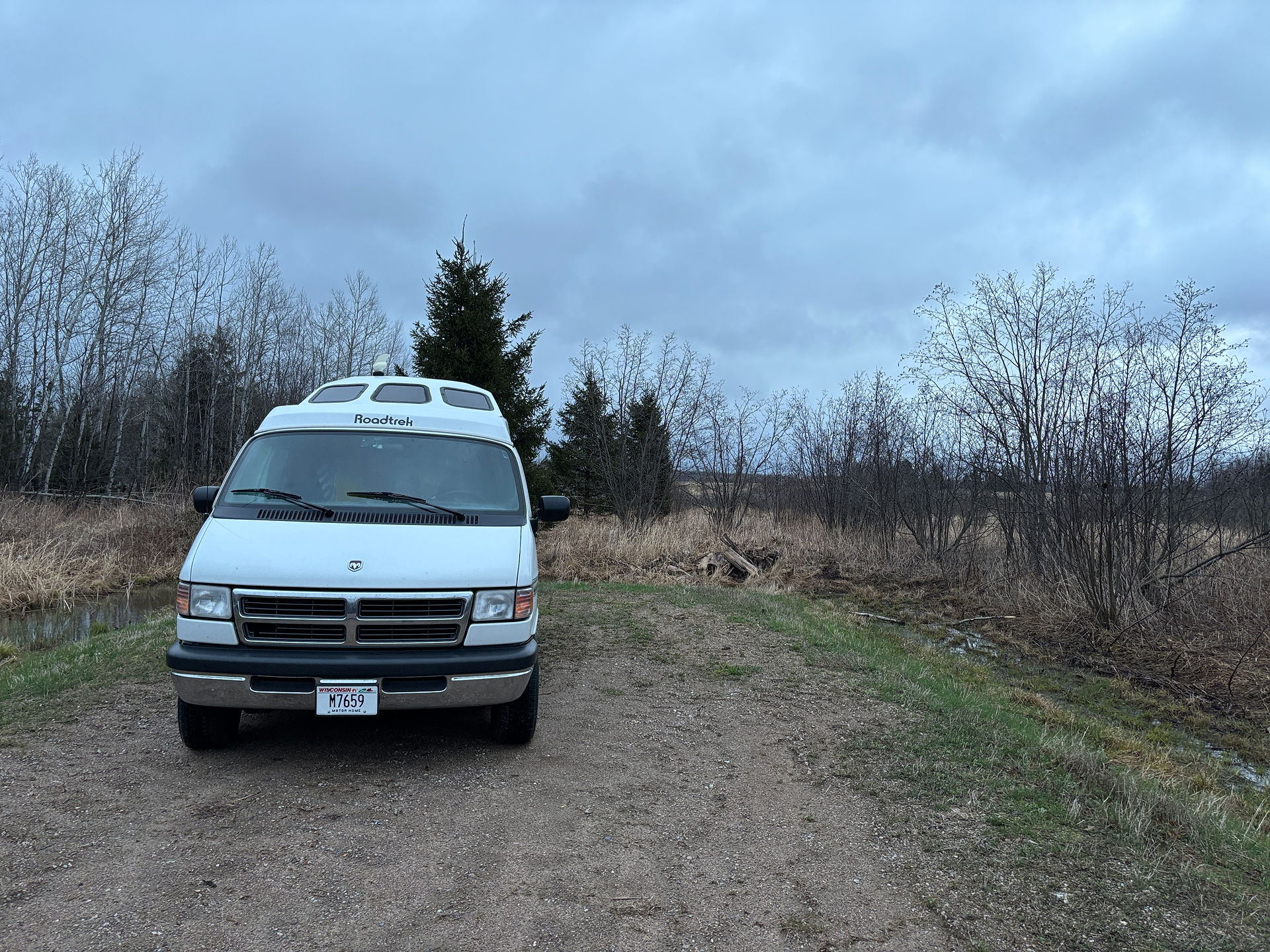 Roadtrek van parked at the dispersed camping site at Ackley State Wildlife Area in Merrill, WI. Nature surrounds van and campsite.