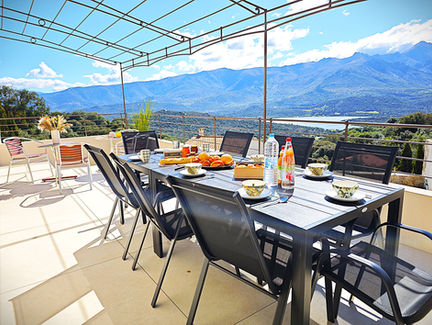 Table dressée avec vue sur les montagnes, petit-déjeuner sur la terrasse.