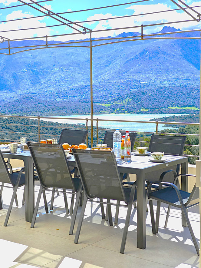 Table préparée sur une terrasse, vue panoramique sur les montagnes et le lac.