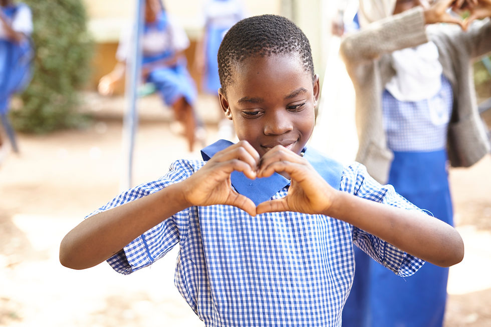 A young student in a checkered blue and white school uniform making a heart shape with her hands