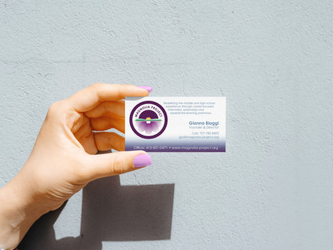 Hand holding business card with logo for Magnolia Project.