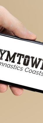 Hand holding phone displaying Gymtowne Gymnastics Coastside logo and branding.