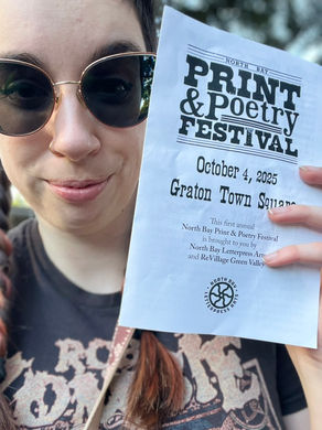 Katharine Cameron in sunglasses holding a flyer for the "North Bay Print & Poetry Festival" on October 4, 2025. Background shows greenery.
