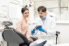 man_dentist_white_apparel_showing_digital_tablet_young_woman_client.jpg