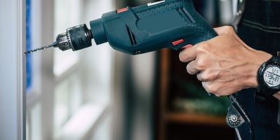 carpenter-holds-drill-drills-window.jpg