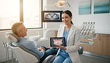 smiling_female_dentist_shows_digital_dental_xray_teeth_anatomy_tablet.jpg