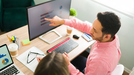 attractive-man-pointing-computer-screen-business-presentation-while-sitting-office-profess