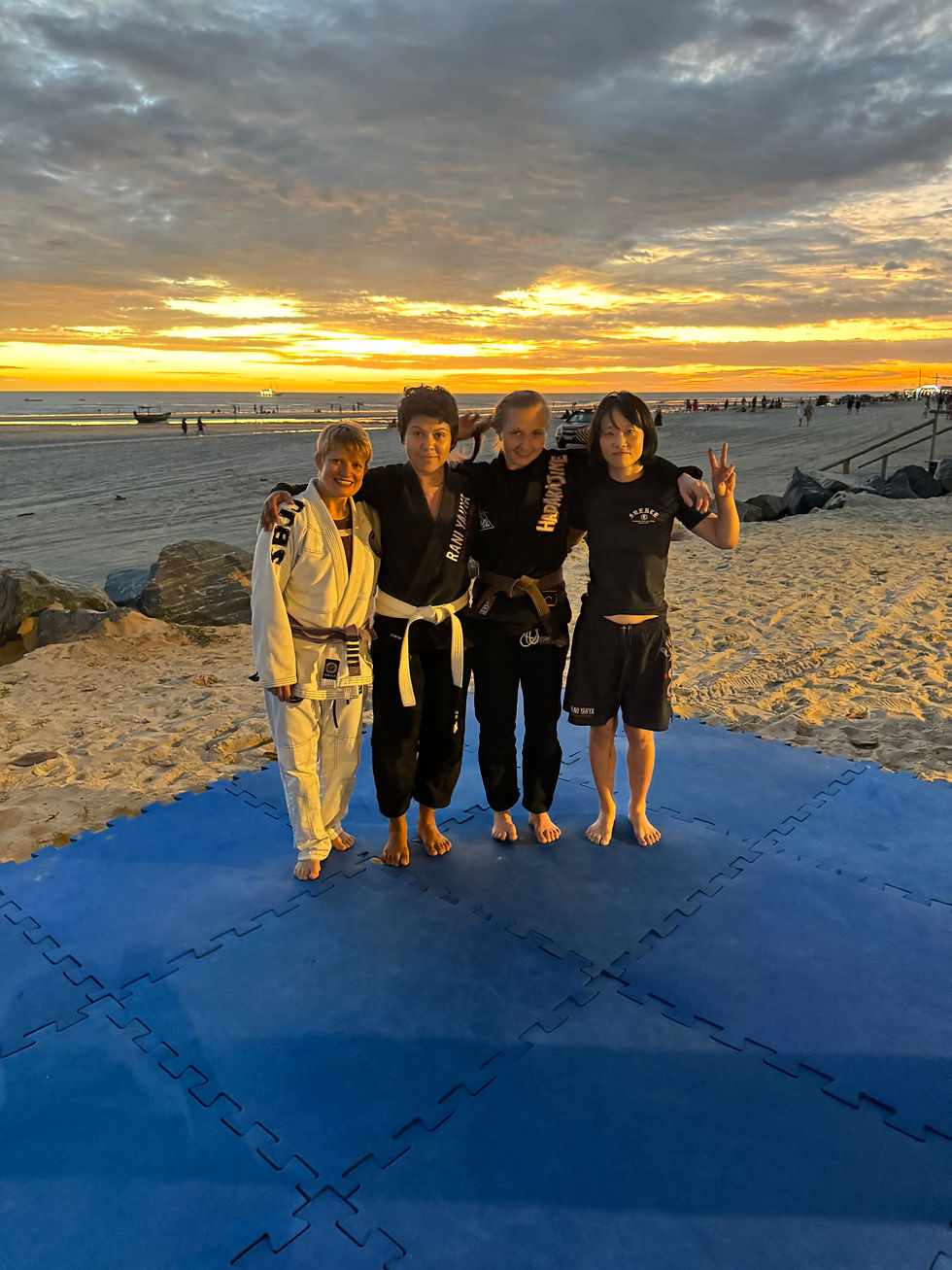 People practicing jiu-jitsu on the beach during sunset