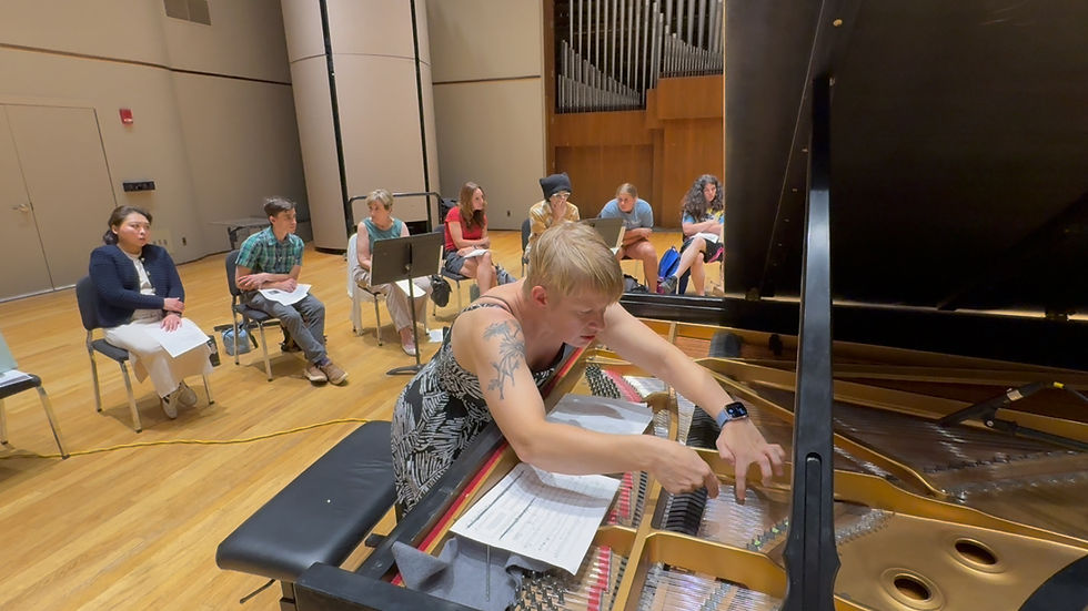 A woman plucks the strings of the piano while the audience on stage watches and listens.