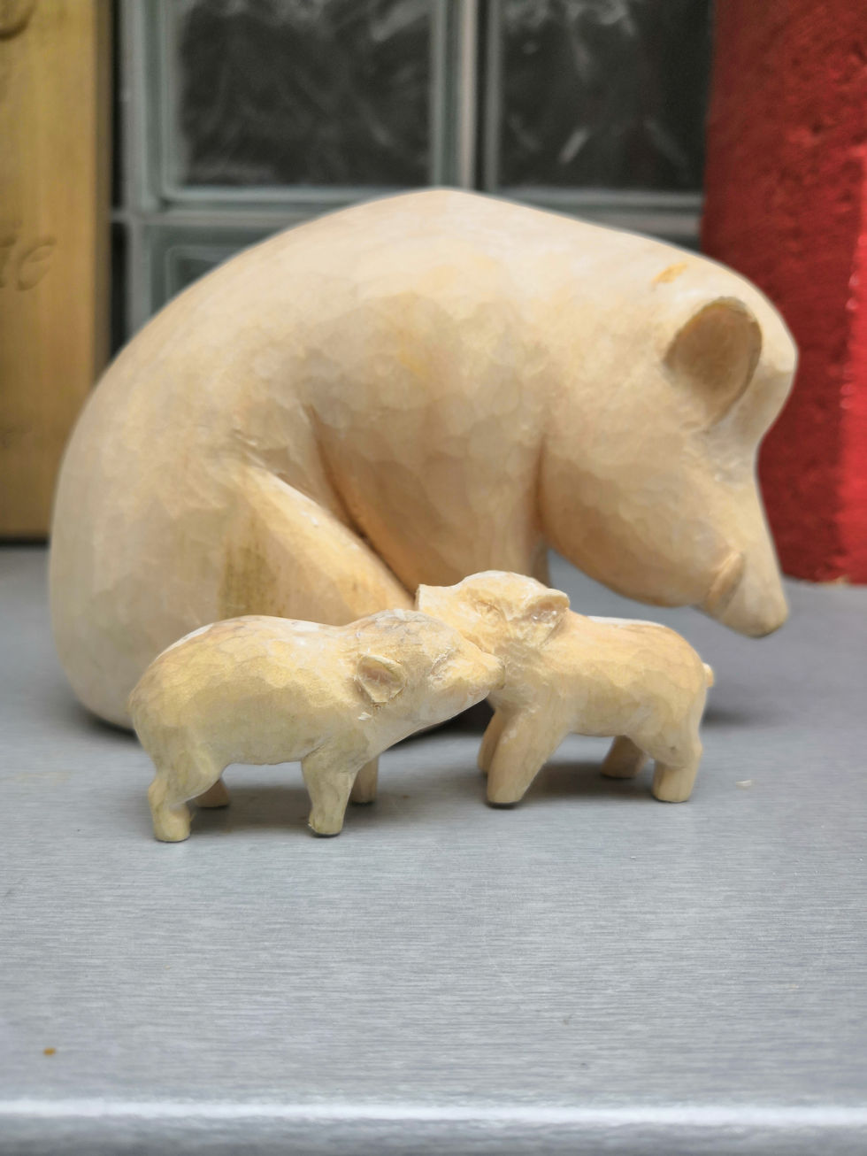 Foto einer geschnitzten, etwa 10 cm hohen Figurengruppe einer Sau mit ihren zwei Frischlingen ohne Sokel, seitliche Aufnahme