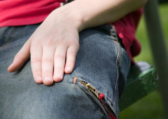 Foto mit Hand, die auf einem Oberschenkel liegt.