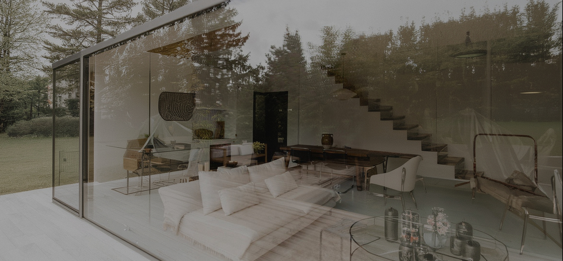A glass-walled residence among pines, with a floating staircase and an open living room inside