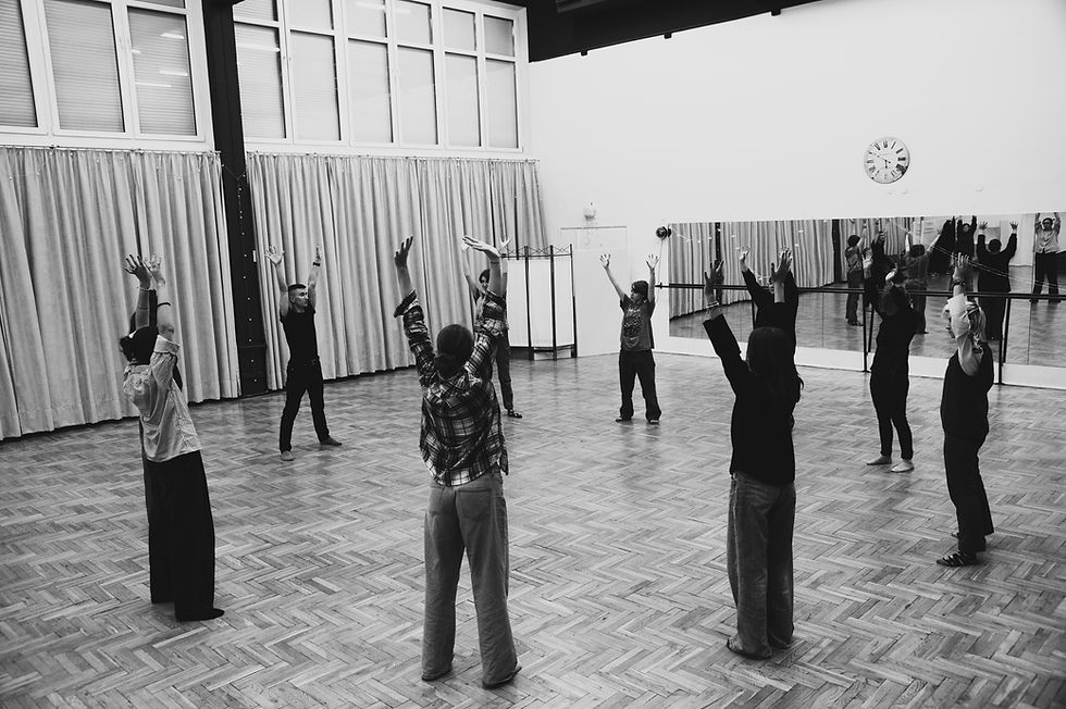 Grupa młodzieży stoi w kręgu z uniesionymi do góry rękami, w czasie warsztatów teatralnych, połączonych z treningiem umiejętności społecznych. Zdjęcie jest czarno - białe. To jedne z naszych warsztatów integracyjnych dla młodzieży w Warszawie