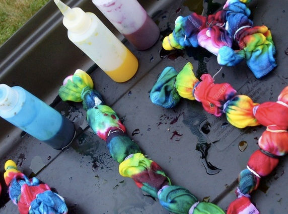 Vibrant Skye Dyes Tie-Dye creations laid out on a tray, with colorful dyes in bottles, showcasing the artful process in its final stages.