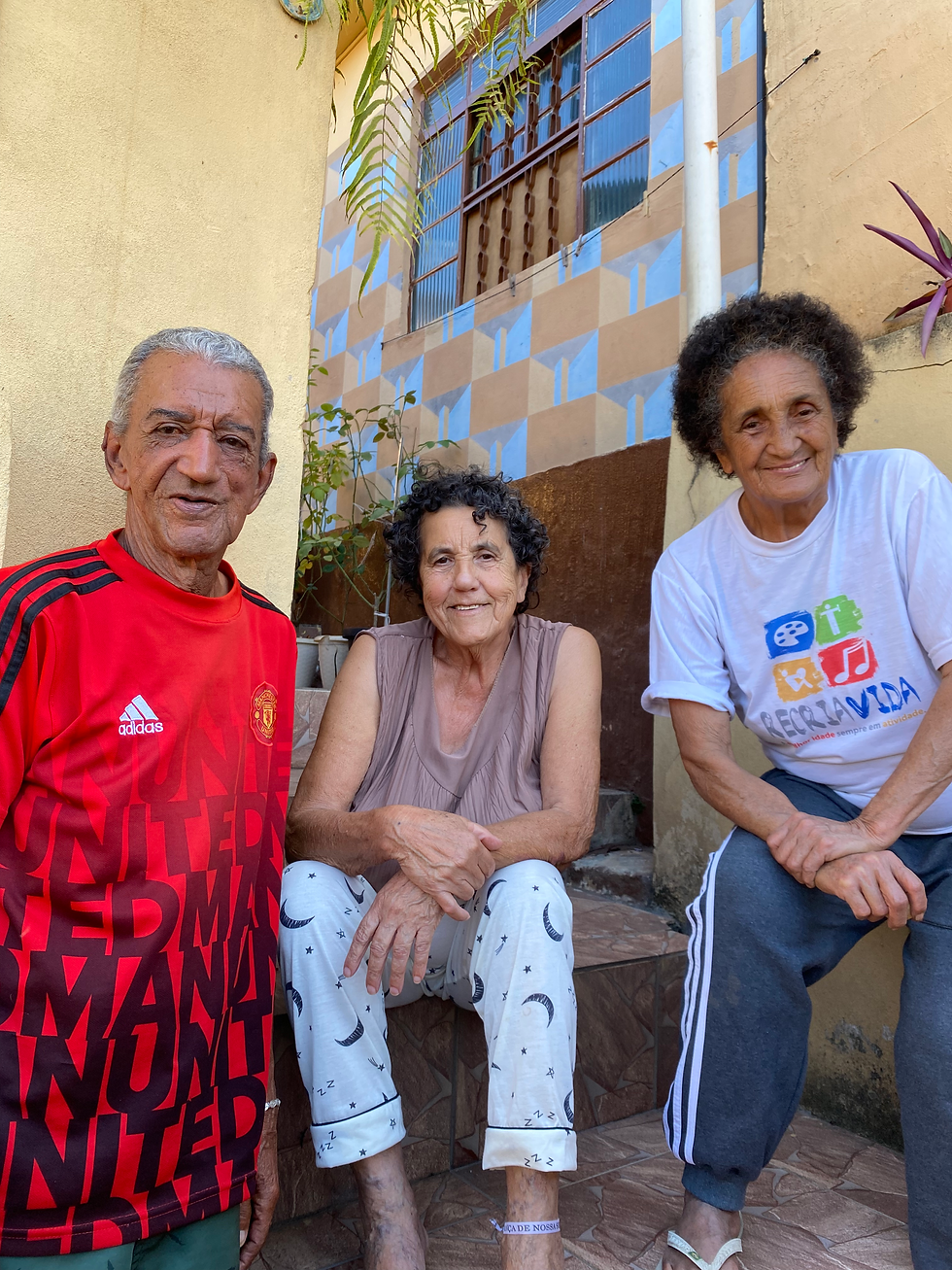 #Pratodosverem: Na foto estão, da esquerda para a direita, João Cristóvão Vilas Boas, Maria Delfina Braga Vilas Boas e Dona Ia. João Cristóvão se posiciona à esquerda da foto de pé, enquanto Maria Delfina Braga Vilas Boas e Dona Ia estão sentadas na escada da entrada da casa de João e Maria.
