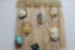#ParaTodosVerem: A imagem apresenta seis máscaras moldadas nos rostos dos detentos, penduradas em uma cortina bege, cada uma com pintura distinta, destacando formas, desenhos, cores e detalhes únicos criados pelos artistas.