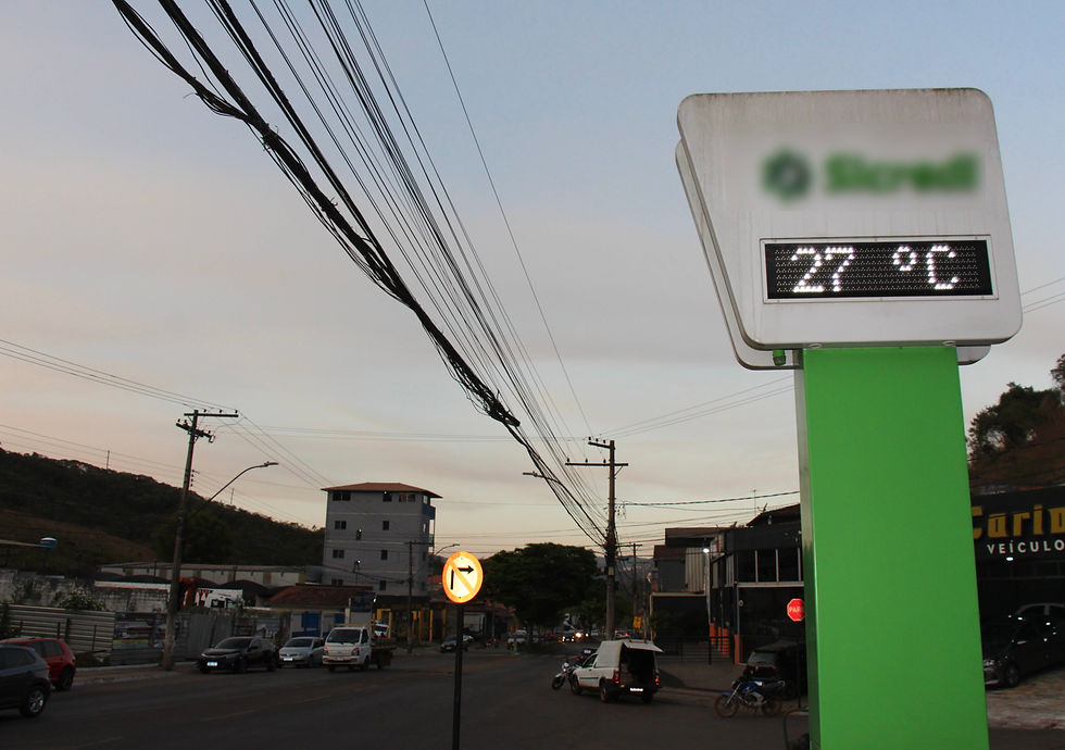 #paratodosverem: No canto direito, um termômetro com suporte verde indica 27 graus Celsius. À esquerda, uma avenida com carros circulando sob um céu que começa a escurecer no fim de tarde.