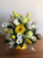 Box arrangement of white, yellow and green flowers such as gerbera, roses, chrysanthemums and lilies.