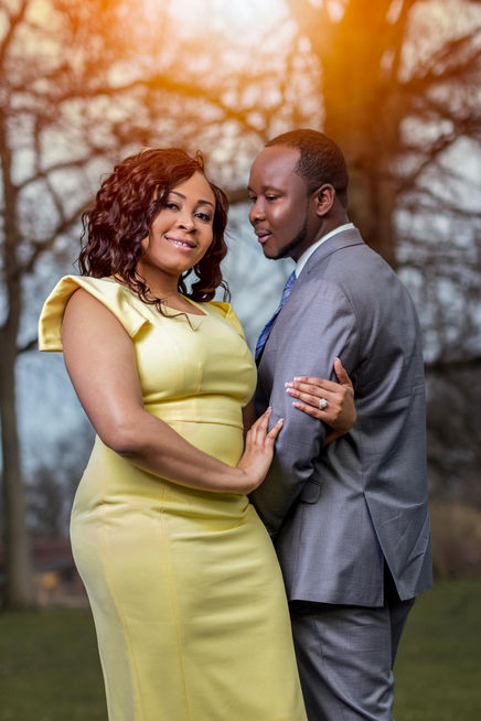 Engaged couple smiling and embracing in a beautiful park during their outdoor engagement session.