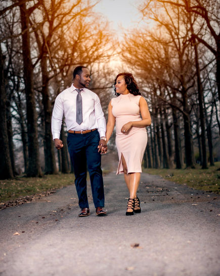 An engaged couple strolling through a forested path during their outdoor engagement in the park.