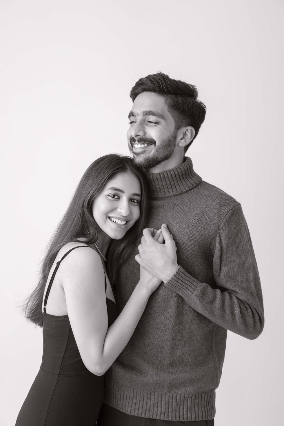 Smiling couple holding hands, black and white photo.