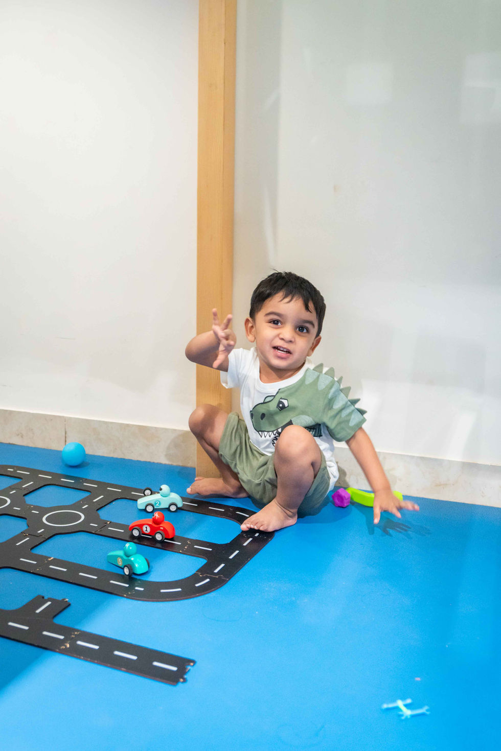 Child playing on a toy road mat indoors.