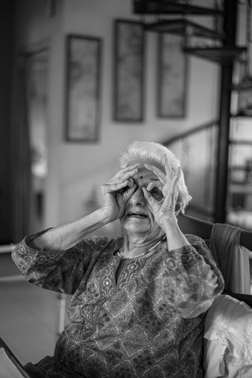 Elderly woman playfully making binoculars with hands.