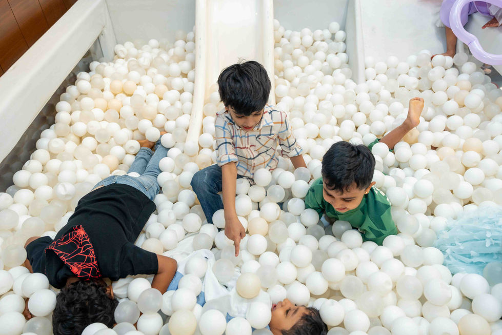Children playing in a ball pit with white balls.
