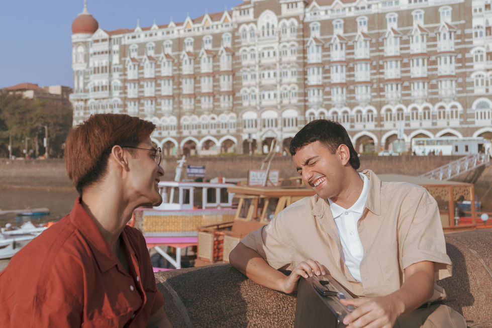 Two people smiling in front of Taj Land's End.