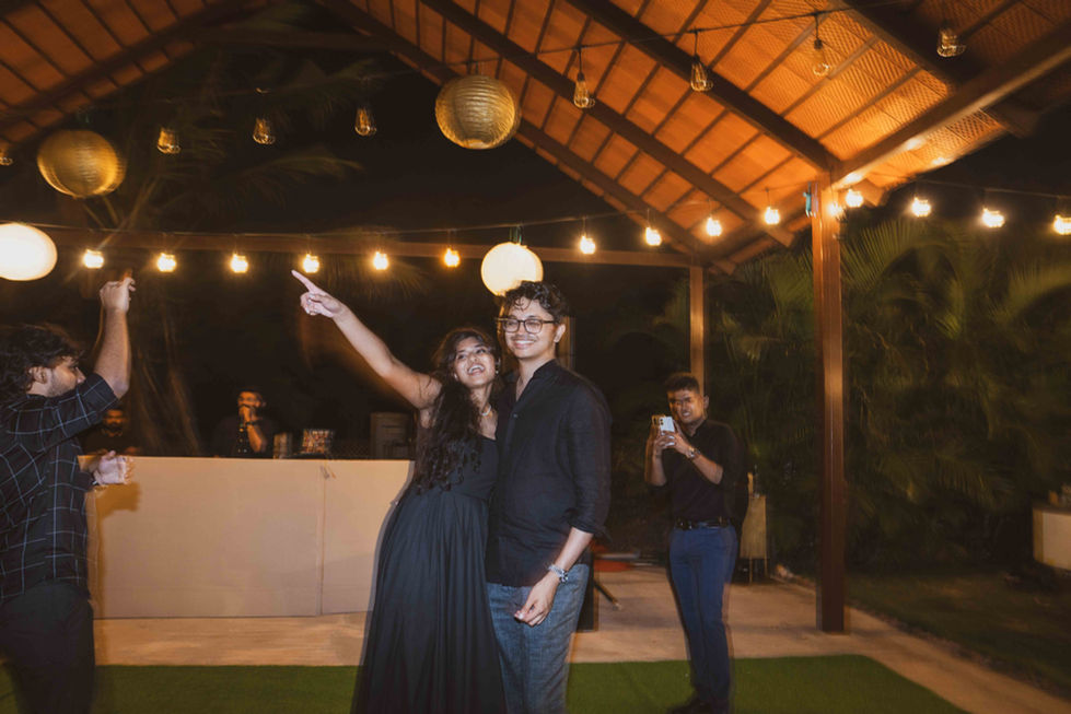 Couple dancing under string lights at outdoor event.