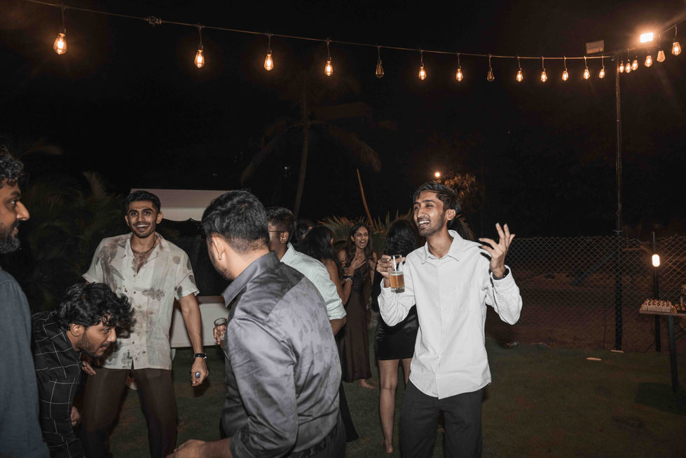 People dancing outdoors under string lights at night.
