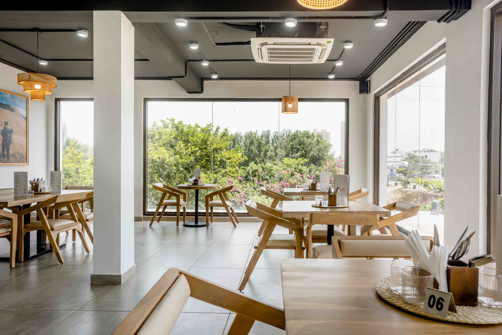 Modern cafe interior with wooden furniture and large windows.