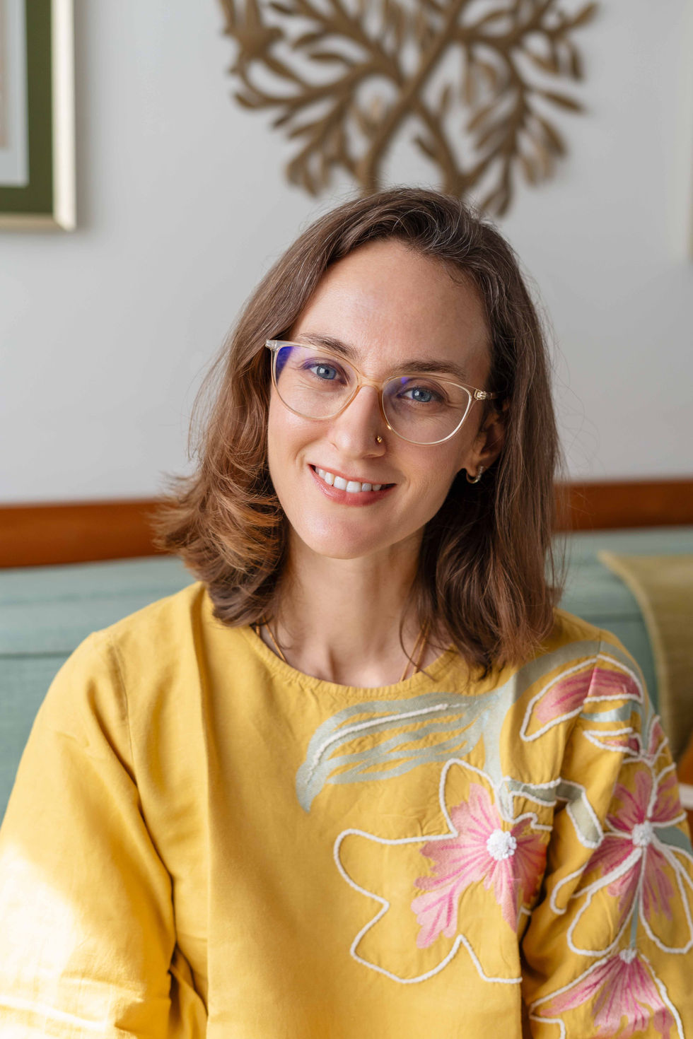 Smiling Ishani Lauren wearing glasses and a yellow top.